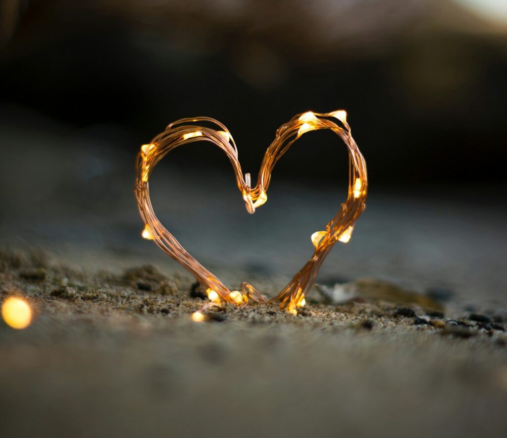 close-up photography of heart shaped fairy lite on brown sand