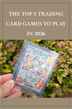 A hand holds a trading card in a plastic sleeve outdoors, with the text The Top 5 Trading Card Games to Play in 2026 above the card. The background shows green foliage and pink flowers.