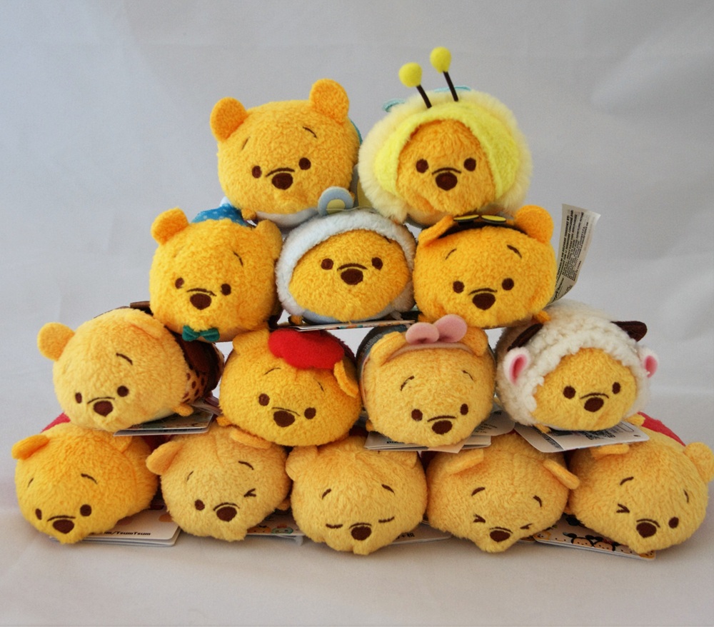 A pyramid of soft toys shaped like Winnie the Pooh, each in different costumes including a bee, lamb, and reindeer, displayed against a plain white background.